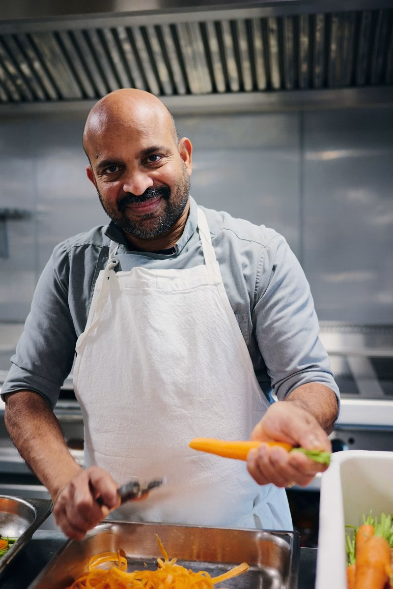 Chef souriant préparant des légumes frais en cuisine lors d'un diner croisière professionnel sur la Seine | Paris en Scène