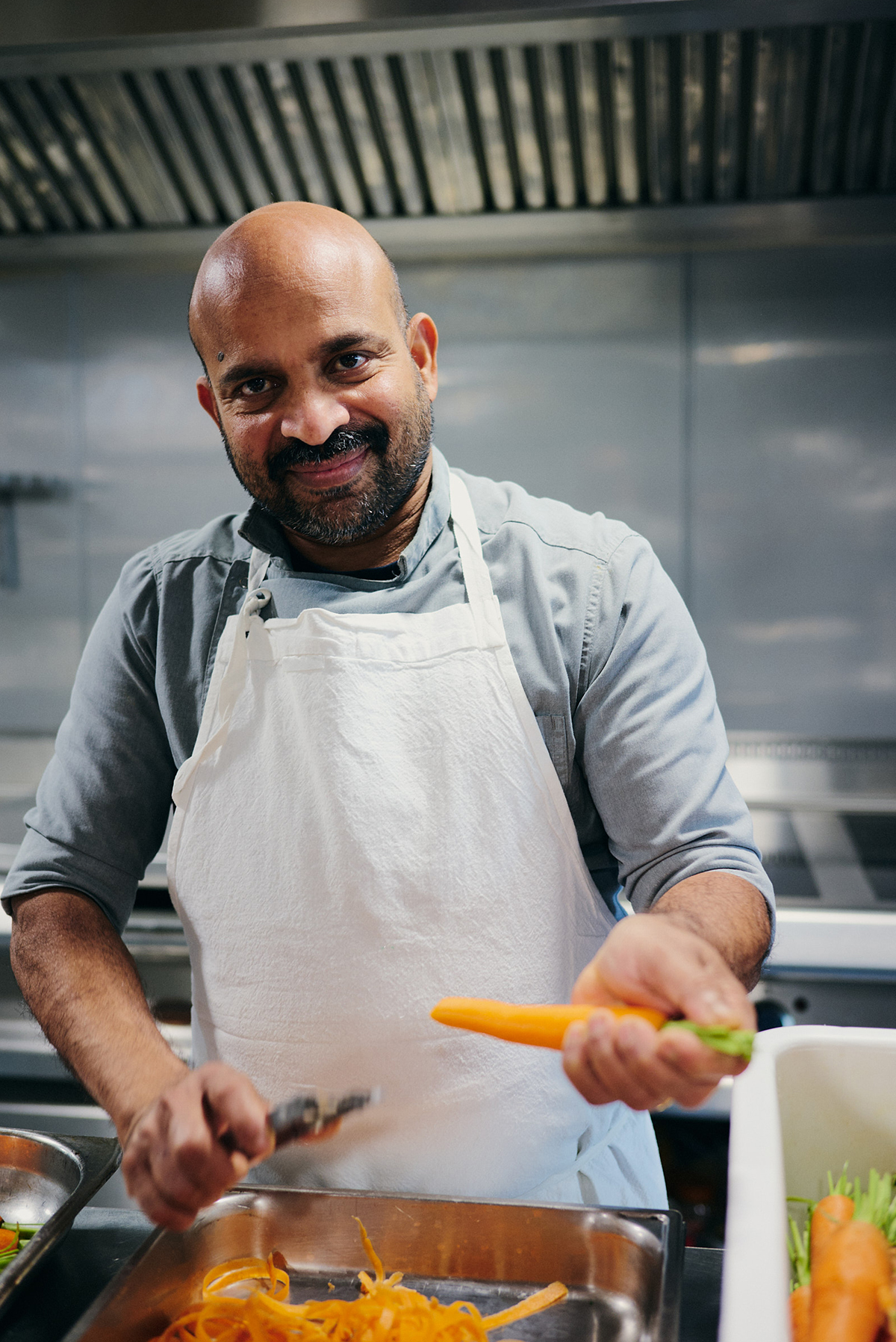 Chef souriant préparant des légumes frais en cuisine lors d'un diner croisière professionnel sur la Seine | Paris en Scène