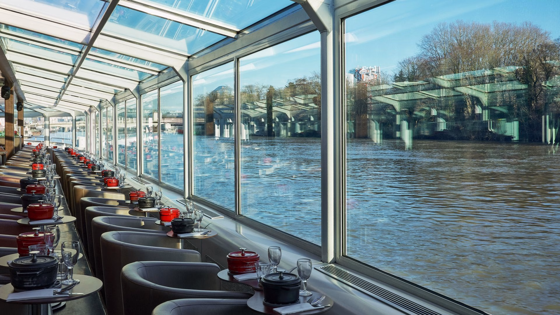 Salle panoramique avec cocottes et vue sur les ponts lors d'un diner croisière lumineux sur la Seine | Paris en Scène