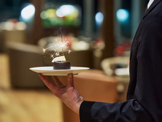 Dessert gourmand avec bougies magiques servi lors d'un dîner croisière sur la Seine à Paris, créant une ambiance festive et joyeuse | Paris en Scène