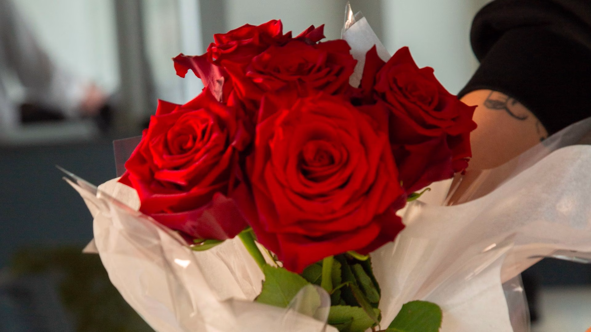 Table décorée avec un bouquet de roses rouges pour un dîner croisière romantique sur la Seine à Paris, offrant une vue sur un pont emblématique | Paris en Scène