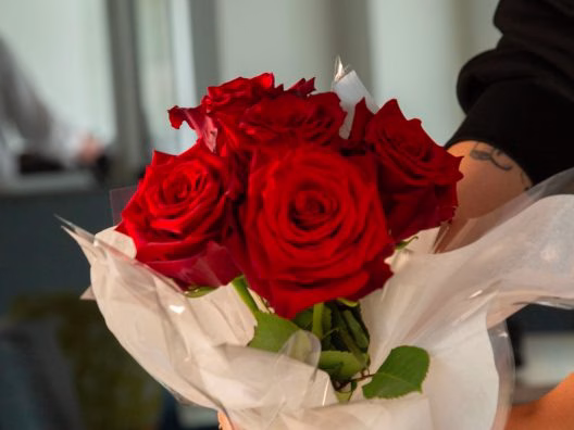 Table décorée avec un bouquet de roses rouges pour un dîner croisière romantique sur la Seine à Paris, offrant une vue sur un pont emblématique | Paris en Scène