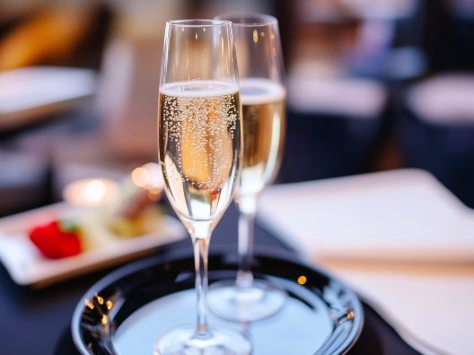 Verre de champagne servi avec des amuse-bouches lors d'un dîner croisière sur la Seine à Paris, offrant une vue pittoresque | Paris en Scène