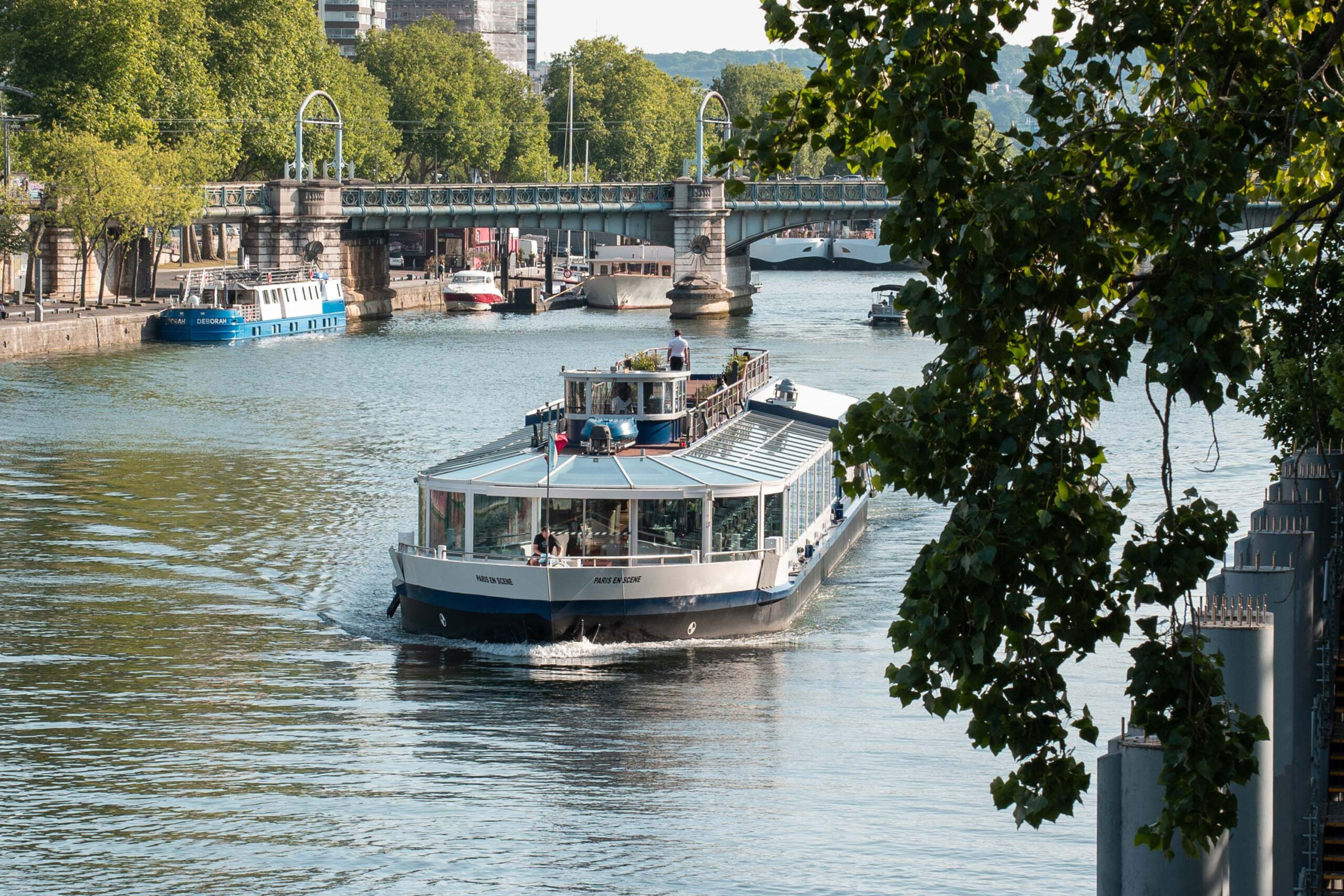 Bateau restaurant naviguant sous les ponts parisiens lors d'un diner croisière paisible sur la Seine | Paris en Scène
